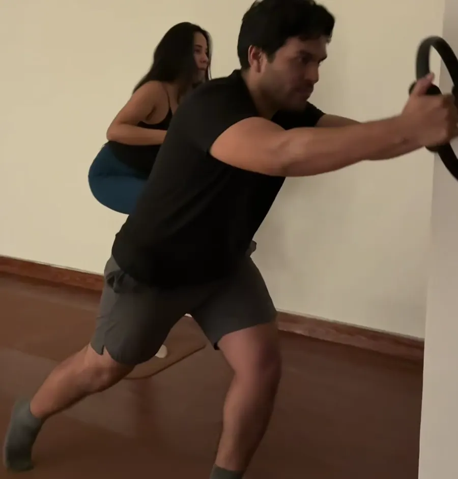 Alumno haciendo una estocada con aro de Pilates en la pared